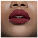 Matte bordeauxrode lippenstift op een mond, met witte tanden zichtbaar.