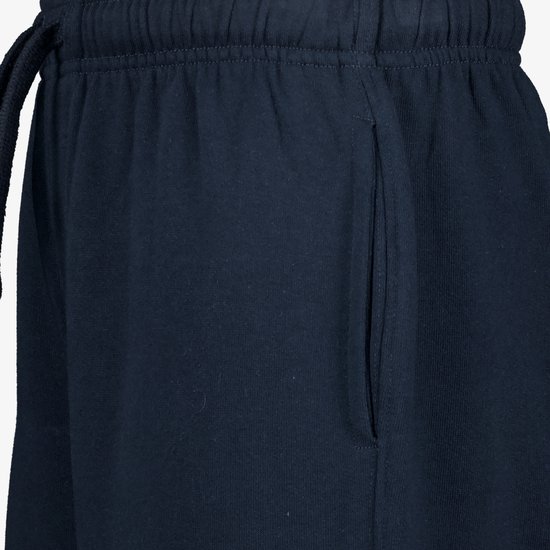 Detail van de tailleband en steekzak van een donkerblauwe joggingbroek.