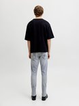 Man in een zwart T-shirt en lichte grijze slim fit jeans, achterkant zichtbaar.