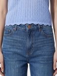 Close-up van een taille met knoopsluiting, gedragen met een lila mouwloze top.