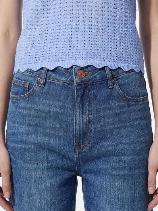 Close-up van een taille met knoopsluiting, gedragen met een lila mouwloze top.