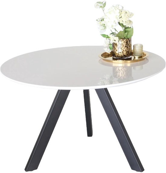 Table ronde blanche avec pieds noirs, décorée d'un vase de fleurs.
