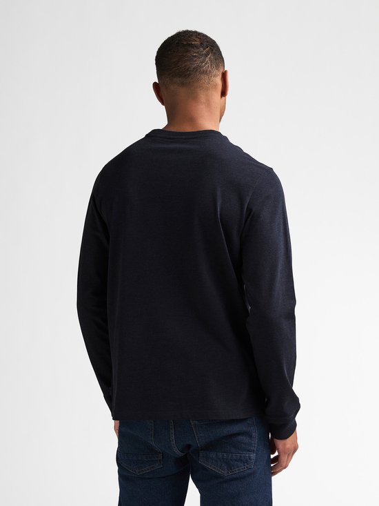 Achterkant man met donkerblauw longsleeve shirt en spijkerbroek.