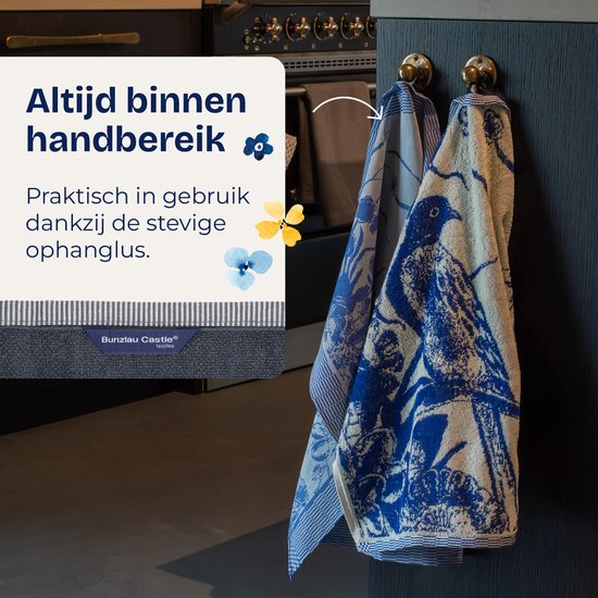 Deux torchons avec des motifs d'oiseaux et de fleurs bleu Delft, suspendus à un crochet.