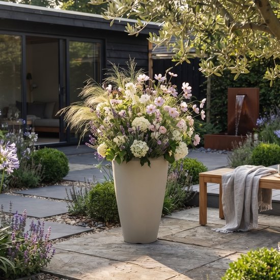 Vase conique gris clair avec un bouquet de fleurs roses et blanches, de verdure et d'herbes.