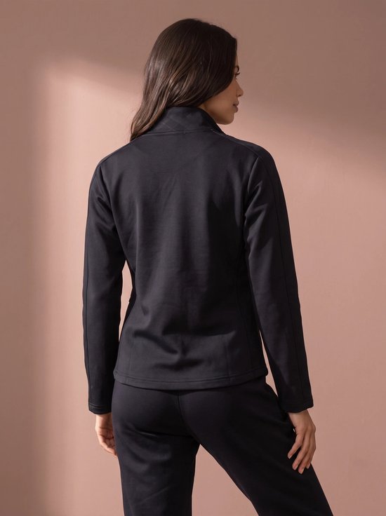 Achterkant van een zwarte sportvest met rits, gedragen door een vrouw.
