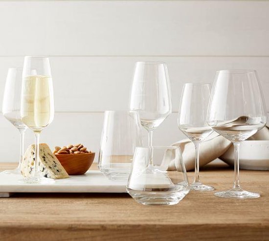 Table avec divers verres à vin et flûtes, remplis de champagne et de vin blanc. Fromage et noix également.