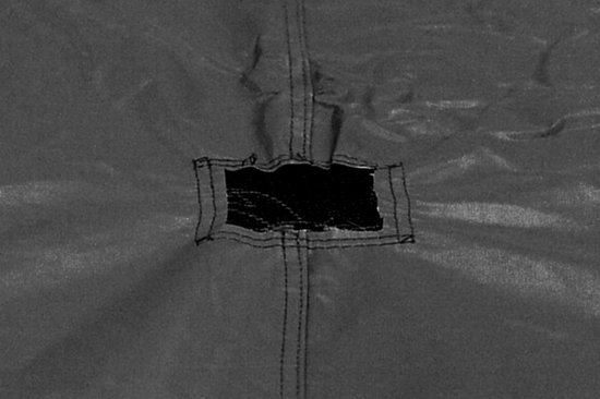 Gedetailleerde view van de ventilatieopening van een donkere trampolinehoes.