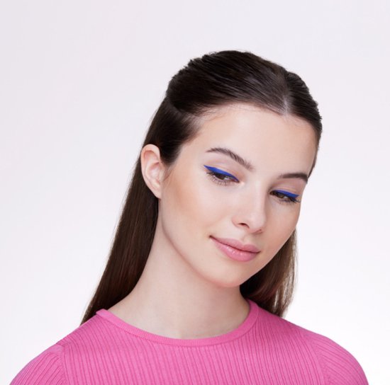 Jong meisje met bruin haar, draagt een roze shirt. Blauwe eyeliner.