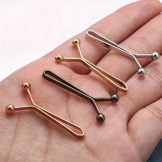 Vier brocheclips in goud, roségoud en zilver met bolle uiteinden, in de hand gehouden.