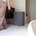 Grijze Jubbly wasmand met deksel, in een badkamer