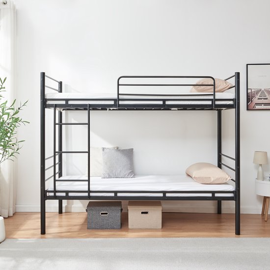Zwart metalen stapelbed met matras, kussens en opbergmanden in een slaapkamer.