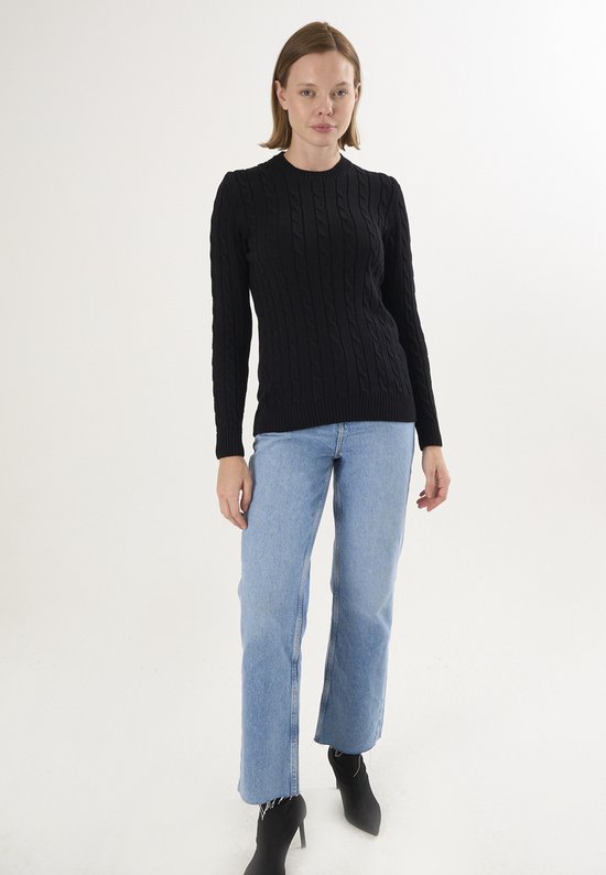 Model draagt zwarte kabel gebreide trui met lange mouwen en blauwe jeans.