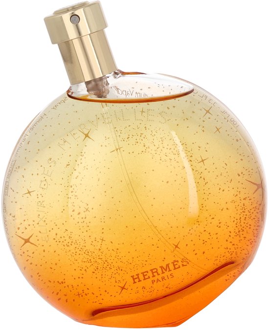 Elixir des Merveilles Eau de Parfum. Rond parfumflesje met goudkleurige dop, oranje-geel glas versierd met sterren en spikkels.