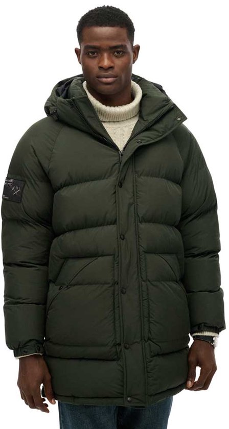 Groene lange gewatteerde parka met capuchon, gedragen door een man met coltrui.