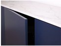 Gros plan d'un meuble de salle de bain bleu foncé avec un plateau en marbre blanc, les portes sont légèrement ouvertes.