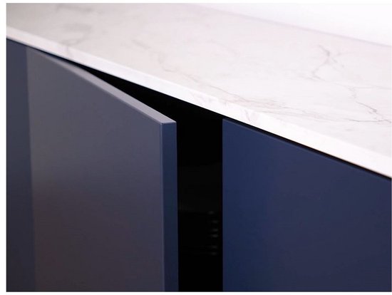 Gros plan d'un meuble de salle de bain bleu foncé avec un plateau en marbre blanc, les portes sont légèrement ouvertes.
