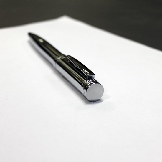 Zilverkleurige pen met clip, op wit papier.