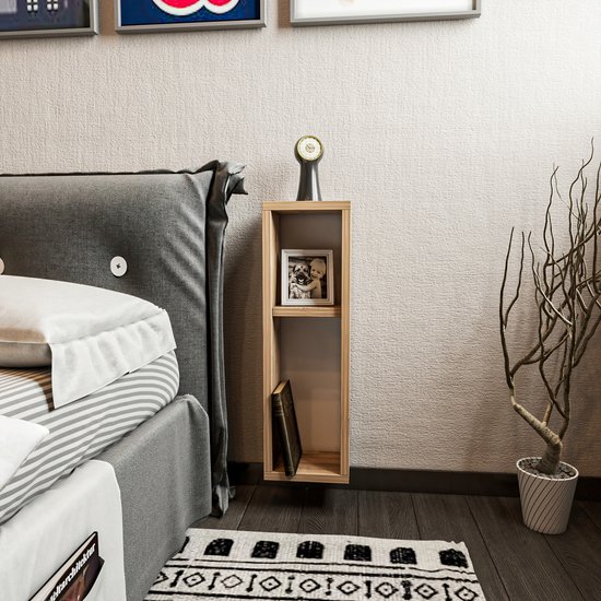 Houten nachtkastje naast een bed met een fotolijstje en boek, in een slaapkamer met poster.