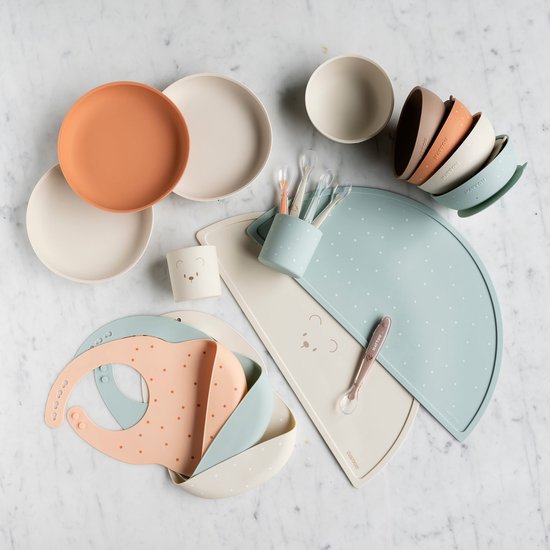 Grand ensemble de vaisselle pour enfants : assiettes, bols, bavoirs, tapis et couverts.