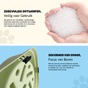 Handen houden kleine witte BPA-vrije pellets vast. Een groene slowfeeder voerbak is onderaan afgebeeld.