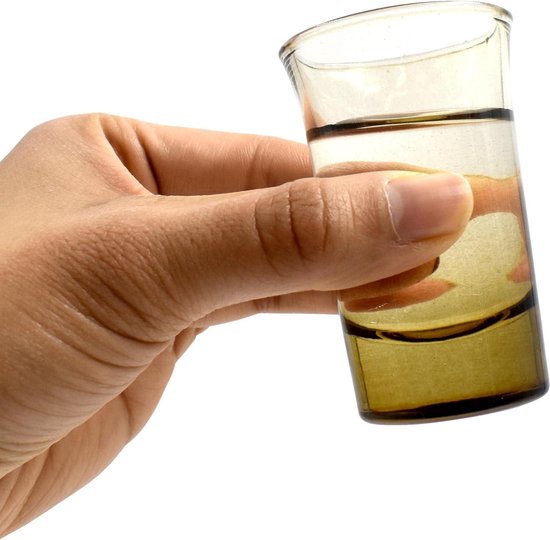Hand met een klein, amberkleurig glas gevuld met vloeistof.