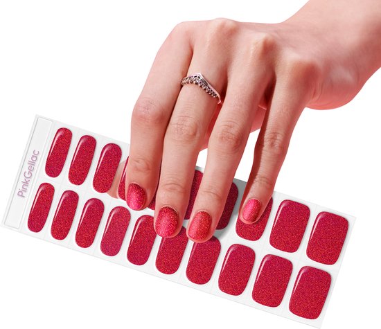 Een hand met een V-vormige ring houdt een vel met rode, glinsterende nagelstickers vast.