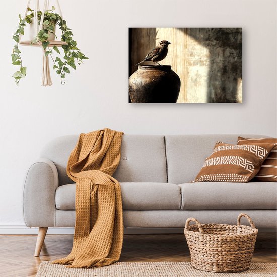 Een bruine vogel op een pot, hangend aan een muur boven een grijze bank in een woonkamer met planten.