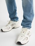 Lichtblauwe sneakers met witte mesh details en een zilverkleurige N-logo. Gedragen door iemand in een spijkerbroek.