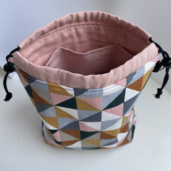 Open projecttas met roze binnenzijde, twee vakjes en een geometrisch patroon van roze, oker, terracotta, groen en grijze driehoeken.