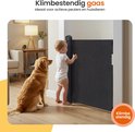 Een baby en een hond kijken naar een opgerold, donkergrijs veiligheidshekje, ideaal voor actieve peuters.