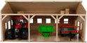 Houten landbouwloods met rode tractor, groene aanhanger en hooi. Drie open ruimtes.