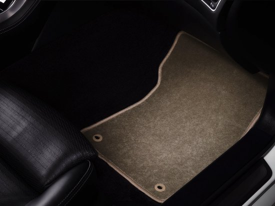 Beige voormat met beige bies geplaatst in de passagiersvoetruimte van een auto.