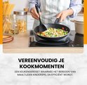 Vrouw in schort met pollepel in een koekenpan met groenten boven een kookplaat.
