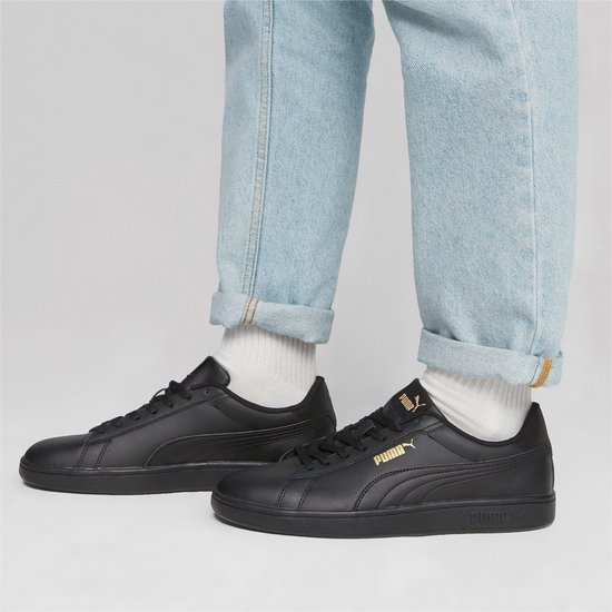 Model draagt zwarte Puma Smash sneakers met lichtblauwe, opgerolde jeans.