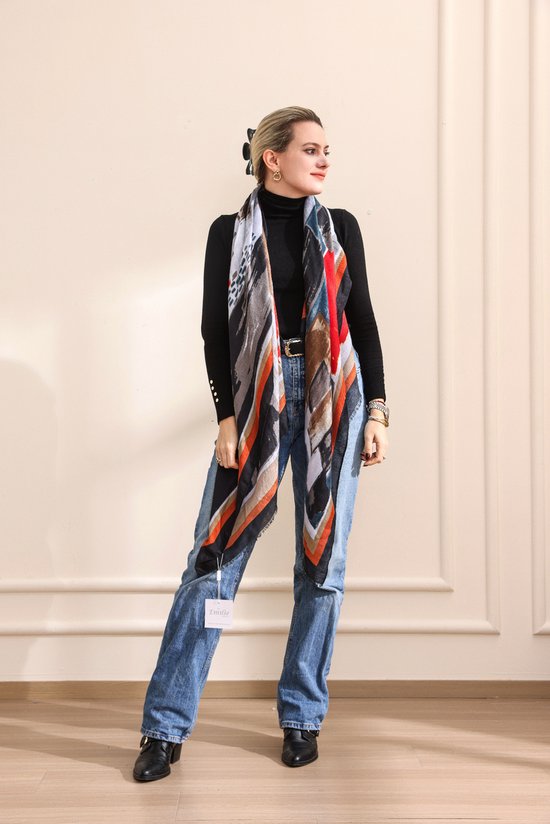 Mannequin portant une écharpe à rayures et imprimé abstrait orange, bleu, beige et noir sur un col roulé noir et un jean.