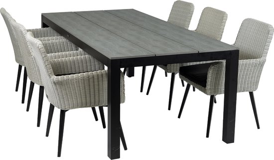 Grijze tuintafel met zes witte vlechtwerk stoelen met zwarte kussens.
