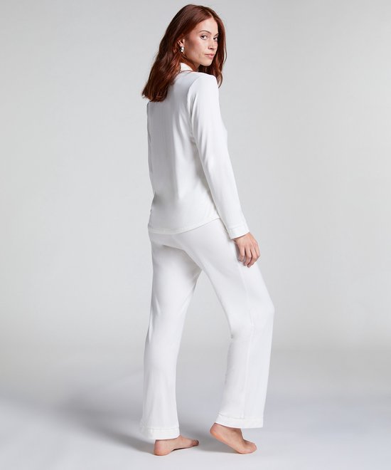 Model van achteren gezien, draagt wit pyjamashirt en broek van jersey in de kleur wit.