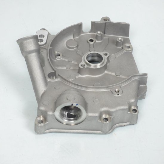 Carter moteur en métal argenté avec plusieurs trous et un raccord fileté.