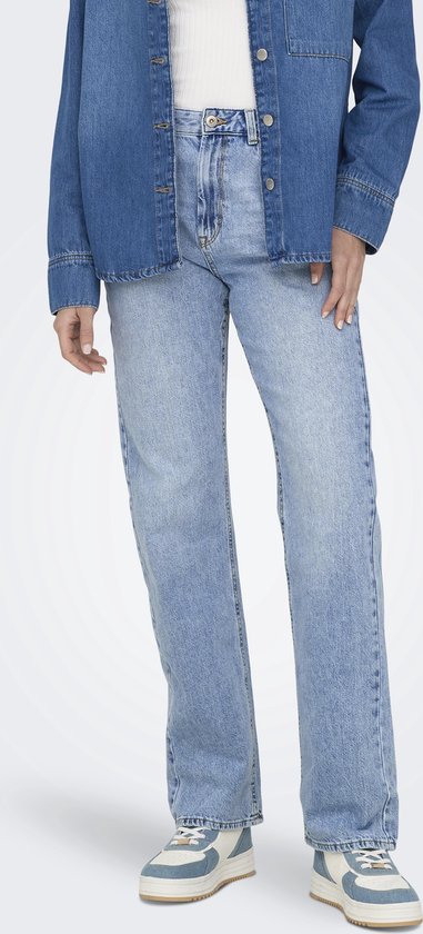 Onderlichaam van een vrouw in een lichtblauwe straight leg jeans en sneakers met blauwe accenten.