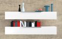 Twee witte zwevende planken aan een betonnen muur, met decoraties en boeken.
