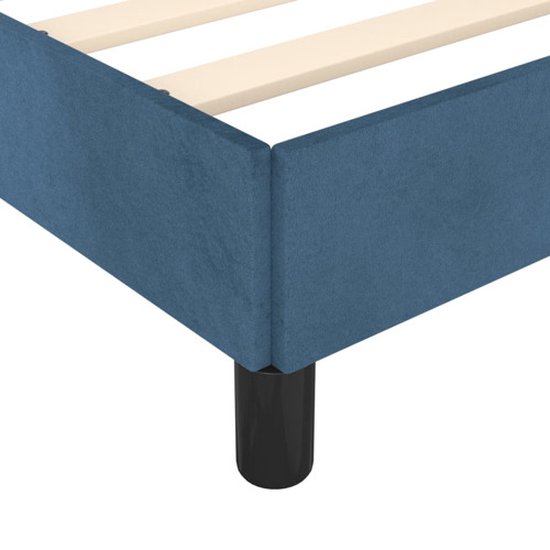 Détail du coin d'un cadre de lit en velours bleu foncé avec un pied noir.