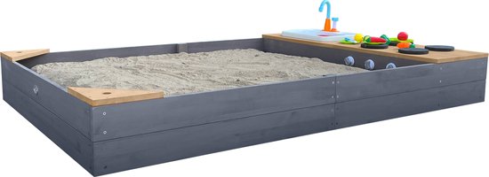 Grijze zandbak met houten speelkeuken aanrecht met speelgoedgroenten, wasbak en blauwe kraan.