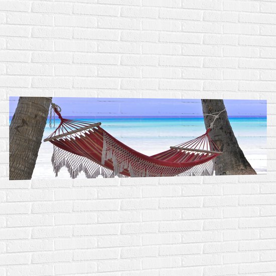 WallClassics - Muursticker - Rode Ibiza Hangmat op Tropisch Strand - 150x50 cm Foto op Muursticker
