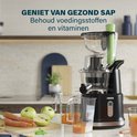 Princess slowjuicer in keuken met vers sap. Met appels, wortels, kiwi's en gember op het aanrecht. De kan bevat vers sap.