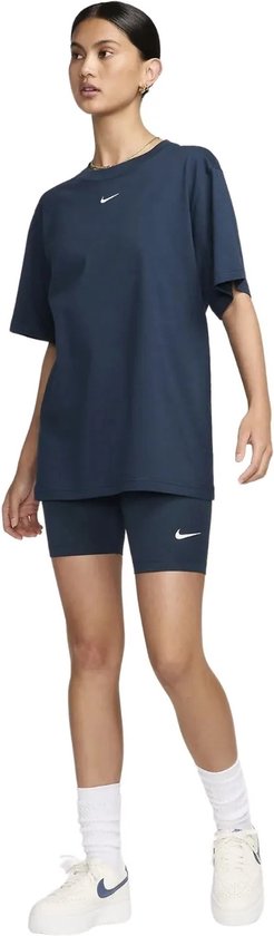 Model in een donkerblauwe Nike outfit: oversized T-shirt en korte tight.