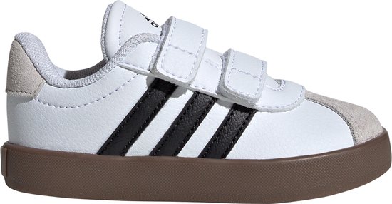 Wit leren Adidas sneakers met klittenbandsluiting, zwarte strepen en bruine zool.