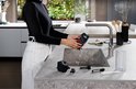 Vrouw spoelt de zetgroep van een DeLonghi volautomaat onder de kraan.
