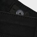 Sluiting van zwarte jeans met verstelbare knopen aan de binnenkant.