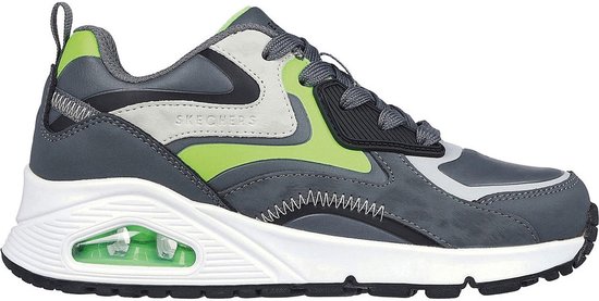 Grijze sneaker met limegroene en witte accenten en een zichtbare luchtdempende zool.